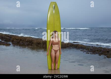 donna in piedi con tavola da surf in piscina Foto Stock