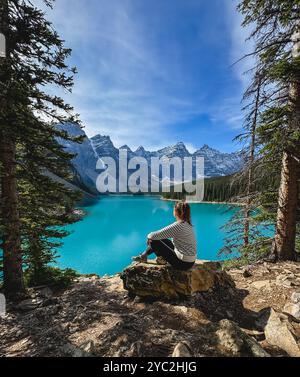 Donna seduta sulla roccia che guarda al lago turchese Moraine a Banff. Foto Stock