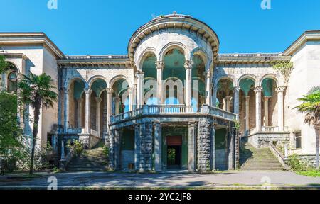 Facciata del sanatorio Medea abbandonato a Tskaltubo, Georgia. L'architettura neoclassica con alte colonne e grandi archi mostra segni di decadimento, circondato dalla natura. Foto Stock