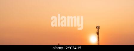 Torre di telecomunicazione con antenna al tramonto. Infrastruttura delle moderne tecnologie di comunicazione. Connettività di rete 5G e telecomunicazioni globali Foto Stock