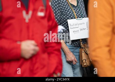 Stoccarda, Germania. 21 ottobre 2024. Persone provenienti da città e comunità presumibilmente minacciate dalla riorganizzazione delle pratiche di emergenza nel Baden-Württemberg stanno partecipando a una manifestazione di fronte alla sede dell'Associazione Baden-Württemberg dei medici di assicurazione sanitaria statutaria (KVBW). A seguito di critiche massicce ai piani di chiusura di pratiche che sono già diventate pubbliche, la (KVBW) presenterà ufficialmente i suoi piani per la futura struttura dei servizi medici di guardia nel sud-ovest. Crediti: Marijan Murat/dpa/Alamy Live News Foto Stock