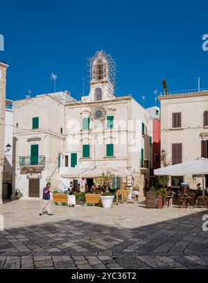 Polignano a Mare Italia 18 settembre 2024, Una giornata di sole in Puglia rivela una vivace piazza dove i visitatori passeggiano tra pittoreschi edifici adornati di verde Foto Stock