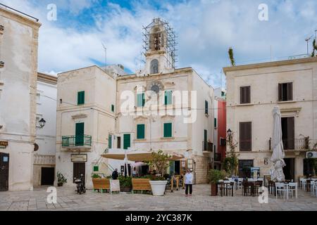 Polignano a Mare Italia 18 settembre 2024, atmosfera serena di una pittoresca piazza pugliese caratterizzata da edifici storici, invitanti posti a sedere all'aperto e frie Foto Stock