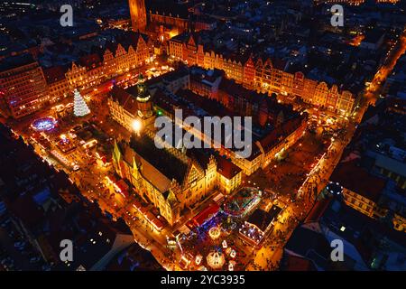 Vista aerea del mercato di Natale di notte con bancarelle illuminate, alberi festivi ed edifici storici a Breslavia, Polonia. Città europea decorata Foto Stock