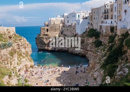 Nell'incantevole città di Polignano a Mare, i visitatori si rilassano sulle coste sabbiose tra le torreggianti scogliere. Le acque azzurre invitano la gente del posto e i turisti Foto Stock