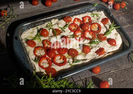 Focaccia appena sfornata con pomodori, olive, aglio ed erbe aromatiche, vista dall'alto, spazio copia. Foto Stock