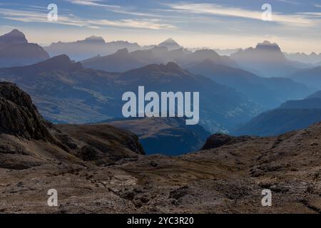 Cielo nebbioso con nuvole e profili montani nella nebbia in autunno. Orizzonte cielo con alte cime montuose che si stagliano nelle Alpi dolomitiche nel blu Foto Stock