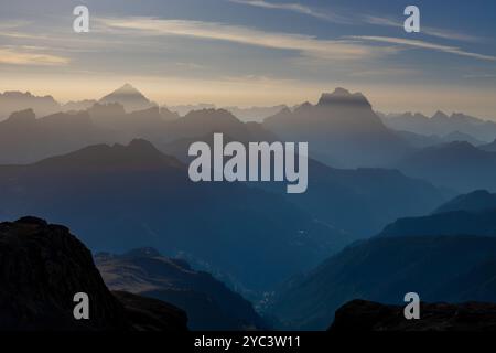 Cielo nebbioso con nuvole e profili montani nella nebbia in autunno. Orizzonte cielo con alte cime montuose che si stagliano nelle Alpi dolomitiche nel blu Foto Stock