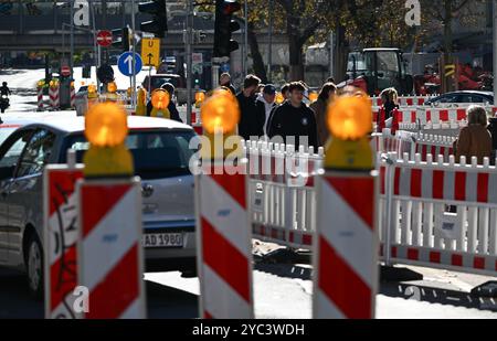 PRODUZIONE - 21 ottobre 2024, Assia, Francoforte sul meno: Segnalatori luminosi con luci lampeggianti guidano il traffico in un cantiere della stazione ferroviaria locale nel quartiere di Sachsenhausen. Concedi più tempo durante la guida attraverso le città dell'Assia. Ciò è dovuto al fatto che i lavori stradali vengono svolti in molti luoghi. L'arretrato dei lavori di ristrutturazione è lungo e non verrà risolto rapidamente. Foto: Arne Dedert/dpa Foto Stock