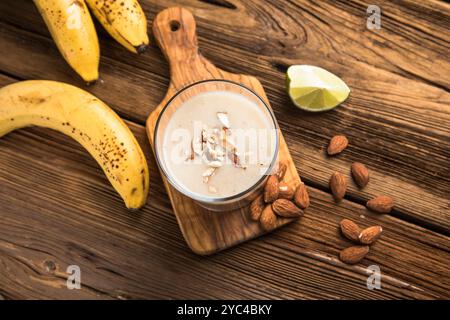 Colazione sana. Frullato di mandorle alla banana con fiocchi di cannella e avena e latte di cocco in vasetti di vetro Foto Stock