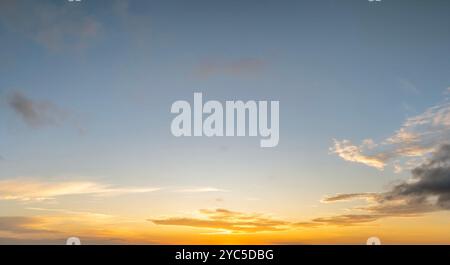 Cielo colorato al tramonto con sole tramontare dietro nuvole di colore arancione e giallo. Foto Stock