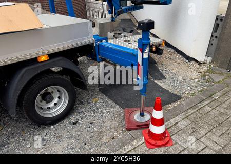 Supporto idraulico di una gru su una superficie pavimentata. I coni stradali sono collocati nelle vicinanze per garantire la sicurezza durante i lavori di costruzione in un luogo urbano. Foto Stock