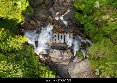 Incredibile paesaggio estivo con le acque della foresta fluviale che cadono in una grande cascata con acqua limpida tra massi rocciosi nella foresta nazionale di Nantahala. Foto Stock