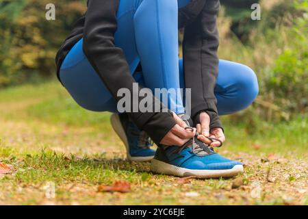 Donna sportiva che si lega i lacci delle scarpe per correre nella foresta. Centro fitness all'aperto. Foto Stock