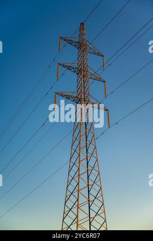 Si tratta di un'immagine di una torre di trasmissione elettrica ad alta tensione, nota anche come un pilone o linee elettriche aeree, al tramonto Foto Stock