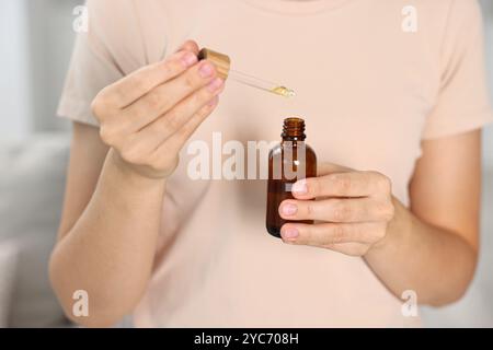 Giovane donna che prende tintura CBD all'interno, primo piano Foto Stock