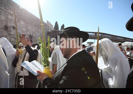 Folla di uomini ebrei con scialli di preghiera o Talith pregano al muro Occidentale mentre tengono in mano le quattro specie durante Sukkot o la Festa dei Tabernacoli. Foto Stock