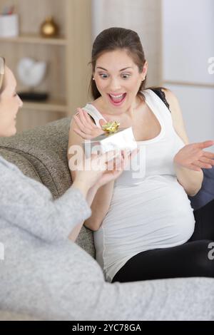 un'amica di medie dimensioni che regala un regalo a una madre incinta Foto Stock