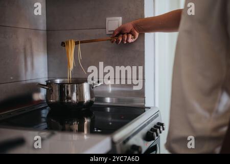 Persona che cucina spaghetti su un piano cottura in una cucina moderna Foto Stock