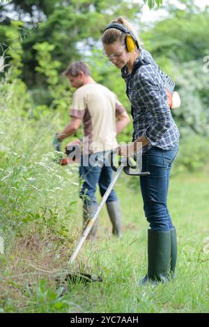 donna e uomo tagliano i confini dell'erba Foto Stock