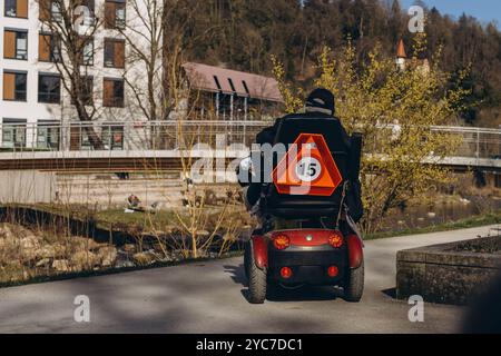 Persona in uno scooter specializzato per disabili, che guida attraverso un parco. Foto di alta qualità Foto Stock