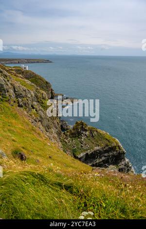 Le scogliere vicino al faro di Anglesey Wales con la Torre di Elin (in gallese: Tŵr Elin) Foto Stock