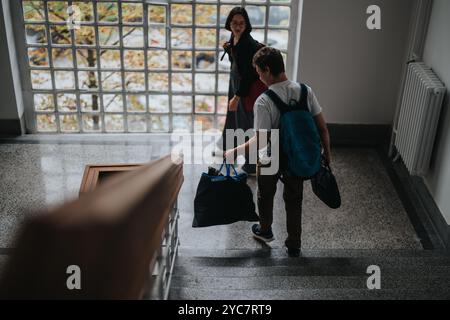Gli studenti camminano giù per scale con zaini nell'edificio universitario Foto Stock