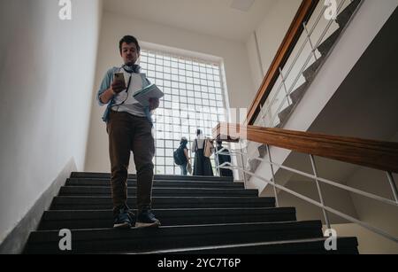 Giovani studenti che camminano sulla scala dell'università con materiali di studio Foto Stock