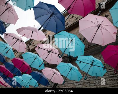 Molti ombrelli aperti appesi nell'aria, fuoco selettivo. Decorazione di strada Foto Stock