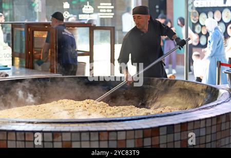 Tashkent, Uzbekistan - settembre 29 2024: Lo chef ha sparato il plov o il pilau in cucina. Il plov è uno dei piatti famosi dell'Asia centrale che di solito involv Foto Stock