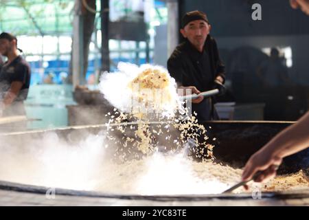 Tashkent, Uzbekistan - settembre 29 2024: Lo chef ha sparato il plov o il pilau in cucina. Il plov è uno dei piatti famosi dell'Asia centrale che di solito involv Foto Stock