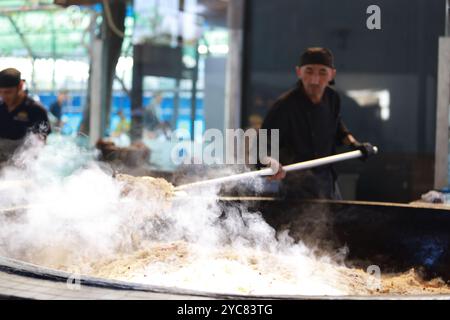 Tashkent, Uzbekistan - settembre 29 2024: Lo chef ha sparato il plov o il pilau in cucina. Il plov è uno dei piatti famosi dell'Asia centrale che di solito involv Foto Stock