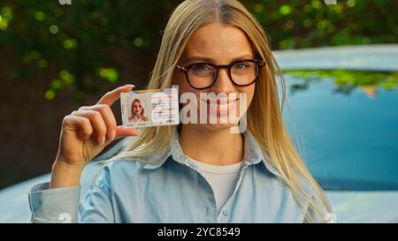 Donna sicura di sé del Caucaso sorriso sorriso risultato patente di guida donna proprietario di una macchina scolastica che mostra un'istruzione felice studente auto Foto Stock