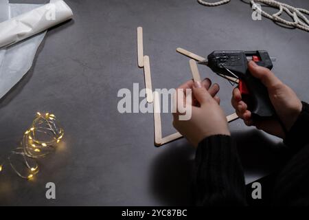 Albero di Natale fatto di bastoncini di gelato. Idea regalo. Fai da te le istruzioni decorazione ecologica. Zero sprechi fatti a mano presenta progetti fai da te per bambini. Vacanze in famiglia. Attività creativa Foto Stock