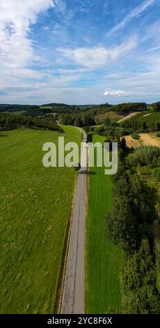 Belscher Aifel, Lengeler, Burg-Reuland, Liegi, Belgio, 22 settembre 2024, Una strada tortuosa attraversa paesaggi verdi e vivaci sotto un cielo azzurro, visto da una vista a volo d'uccello Foto Stock