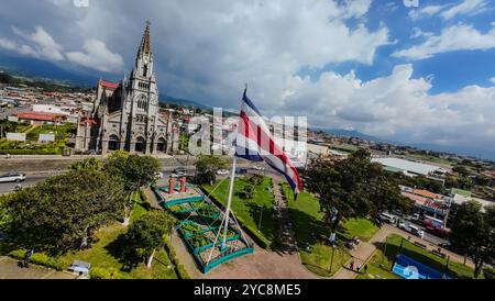 Splendida vista aerea FPV della bandiera Bicentenaria della Costa Rica nel Parco Coronado con la chiesa gotica. Costa Rica Foto Stock