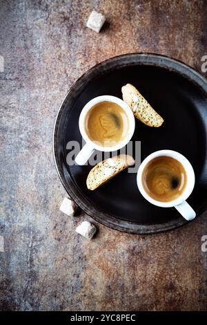 Cantuccini (biscotti italiani) e due tazze di caffè su fondo rustico in pietra. Copia spazio. Foto Stock