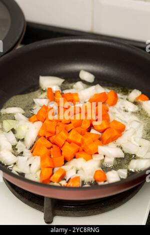 Le cipolle finemente tritate e le carote fresche vengono fritte nel burro e preparate con patè Foto Stock