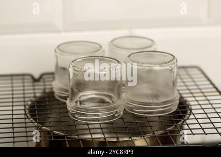 Vasetti di vetro sopra una vaschetta in acciaio inox durante la sterilizzazione a vapore per l'inscatolamento domestico Foto Stock