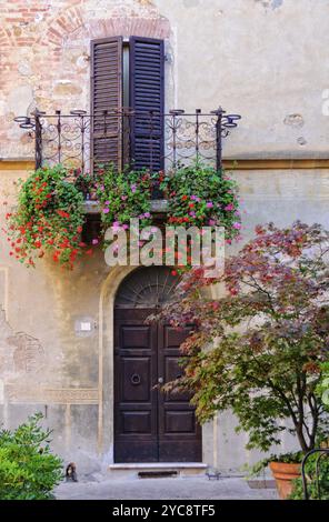 Persiane metà chiuse durante la siesta su un balcone decorato da fiori fioriti a Pienza, Toscana, Italia, Europa Foto Stock