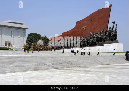 08.08.2012, Pyongyang, Corea del Nord, Asia, Un gruppo di figure in bronzo e un'enorme bandiera fanno parte di una scultura presso il Mansudae Grand Monument nel Nort Foto Stock