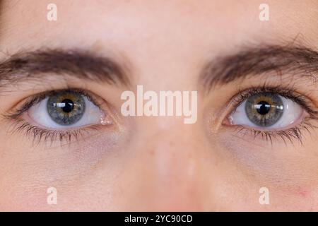 Primo piano degli occhi blu della donna che guardano intensamente, catturando il momento di riflessione, a casa Foto Stock