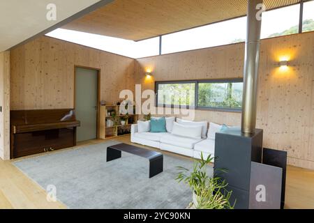 Soggiorno moderno con comodo divano, pianoforte e ampia finestra con vista a casa Foto Stock