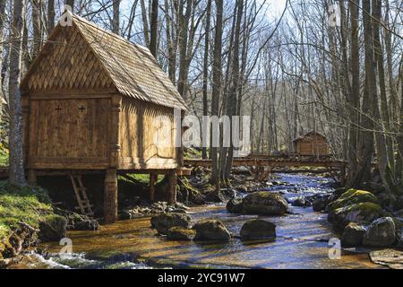 Belle capanne in legno da un ruscello nella foresta e passerella sull'acqua Foto Stock