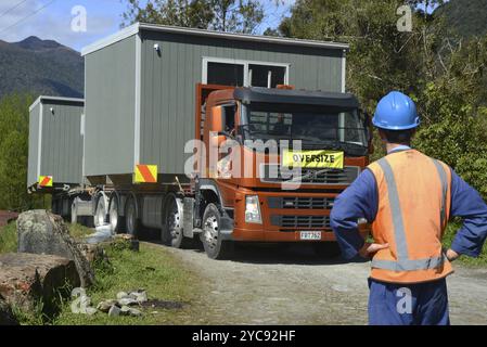 GREYMOUTH, NUOVA ZELANDA, 21 OTTOBRE 2020: Un lavoratore di costruzione attende l'arrivo di un operatore di gru che solleverà un piccolo edificio da un camion ont Foto Stock