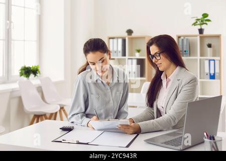 Una giovane donna cliente prende un prestito e firma un contratto in banca Foto Stock