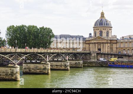 La gente cammina sul Ponte delle Arti (Pont des Arts) sul fiume Senna tra l'Istituto di Francia (Institut de France) e il Louvre, Parigi, fra Foto Stock