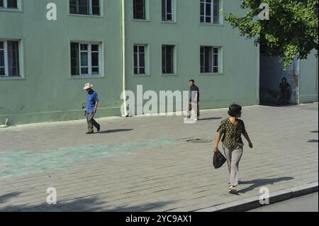 08.08.2012, Pyongyang, Corea del Nord, Asia, i pedoni camminano su un ampio e altrimenti deserto marciapiede lungo edifici residenziali a più piani nel c Foto Stock