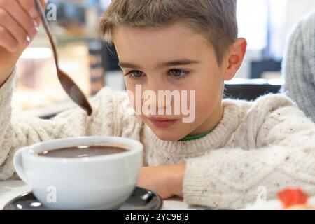 Ragazzo caucasico che beve cioccolata calda in un caffè in inverno Foto Stock
