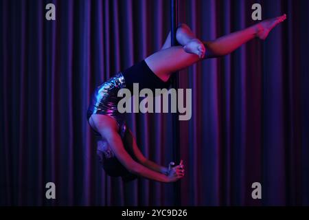 Esibizione di Pole Dance in una stanza poco illuminata Foto Stock